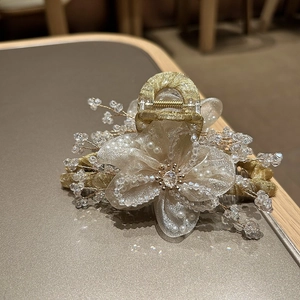 Dettaglio del fermaglio per capelli a fiore in organza con strass, perle e metallo