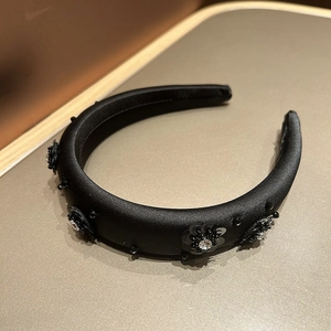 Detailed view of black satin headband with handmade sequin flowers and rhinestone crystals