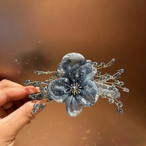 Dettaglio molletta per capelli a fiore in organza blu con perline di cristallo e oro