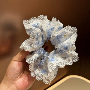 Détail d'un chouchou bleu clair à fleurs avec bordure en dentelle blanche festonnée