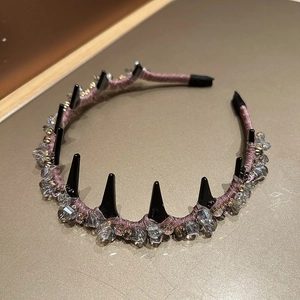 Détail d'un serre-tête en tissu violet style punk avec pointes noires et strass