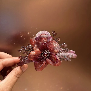 Dettaglio della molletta per capelli a fiore in organza bordeaux con perle di cristallo