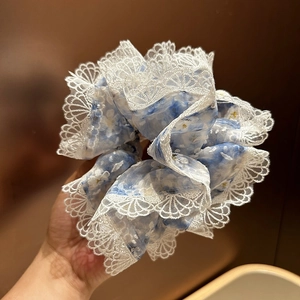 Gros plan détaillé d'un chouchou bleu à fleurs avec bordure élégante en dentelle blanche