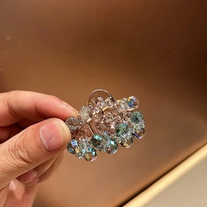 Detail of a mini hair claw clip featuring colorful faceted crystal beads and gold spring