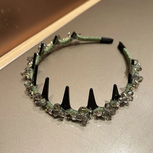 Vue détaillée du serre-tête en satin vert avec cristaux gris et pointes punk noires