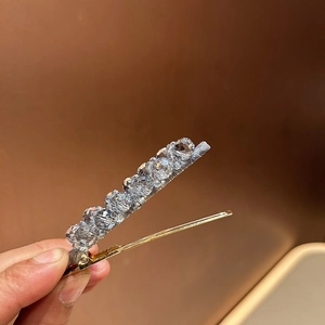 Close-up of sparkling crystal beads on a golden alloy hair clip with faceted textures