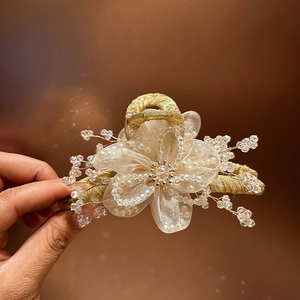Dettaglio del fermaglio per capelli dorato con petali in organza, perle e cristalli