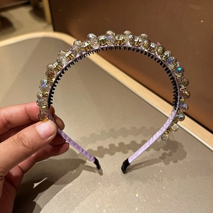 Detailansicht eines lila Satin-Haarreifs mit funkelnden facettierten Kristallen