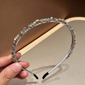 Detail of luxury rhinestone headband with gold beads and crystals on silver fabric base