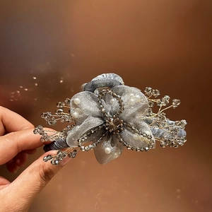 Dettaglio macro di un fermaglio per capelli a fiore in organza fatto a mano con cristalli