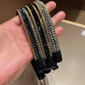 Detail view of crystal beaded headband with gold chain trim and padded black fabric base