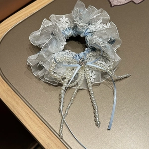 Détail d'un chouchou floral avec dentelle, glands de perles et cristal central