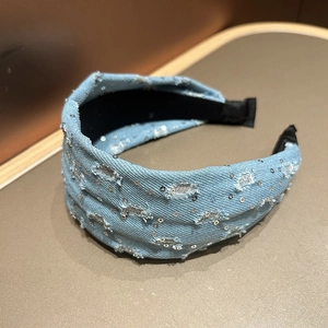 Detail of light blue denim headband with silver sequins and distressed retro texture