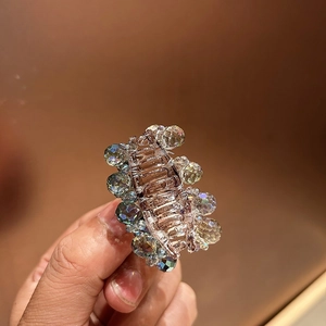 Detail of a mini crystal hair claw clip with colorful iridescent beads on brown resin