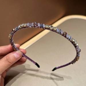 Detailed close-up of handmade purple crystal beads and rhinestones on a slim satin headband