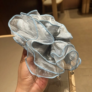 Detail of light blue organza scrunchie featuring hanging clear crystal charms and ruffles