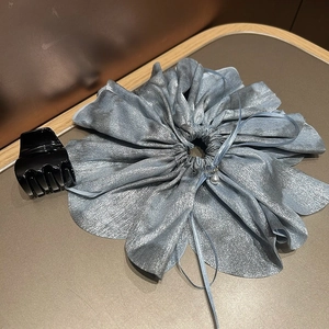 Blue metallic scrunchie with pearl charm and black glossy hair claw clip on desk