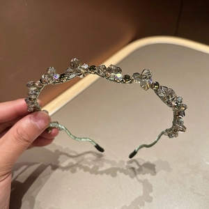 Detailed close-up of handmade green crystal headband with multifaceted sparkling beads