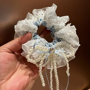 Détail de chouchou fleuri bleu avec bordure en dentelle et nœud en perles