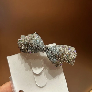 Gros plan d'une barrette à cheveux en forme de nœud argenté avec cristaux chatoyants
