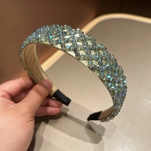 Detailed macro view of woven crystal beads on a champagne gold wide headband surface