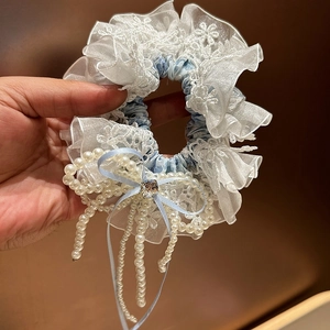 Détail d'un chouchou à fleurs avec nœud en soie bleue et glands en perles