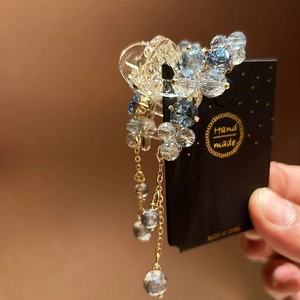 Handmade hair claw clip with blue crystal beads and metallic tassel on display card