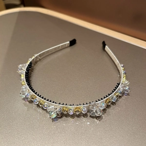 Détail d'un serre-tête en satin argenté orné de cristaux et peigne antidérapant