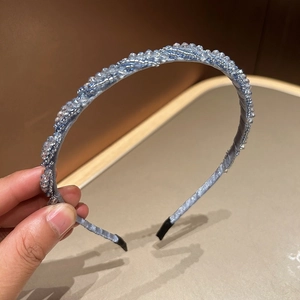 Detail eines blauen Kristall-Haarreifs mit aufwendig handgewebten Flechtmustern