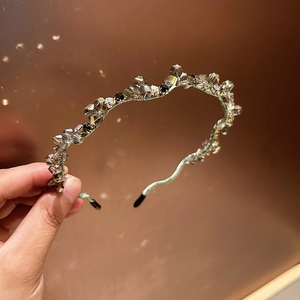Detailed close-up of wavy metal headband featuring sparkling champagne and clear crystals