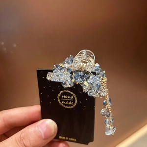 Makroaufnahme der himmelblauen Kristall-Haarklammer mit goldenen Kettenquasten-Details