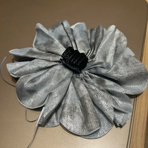 Detailed view of oversized silk fabric flower hair claw with silver luster and metal clip