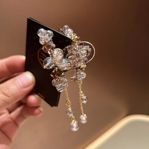 Detailed close-up of champagne crystal flower hair claw with dangling beaded chains