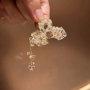 Detail einer champagner-goldenen Haarklammer mit Kristallen und hängender Quaste