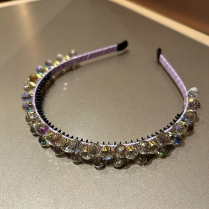 Detail eines lila Satin-Haarreifs mit facettenreichen Kristallen und Goldkrallen