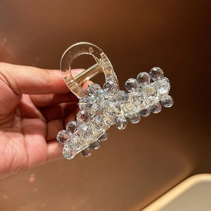 Macro detail of acrylic hair claw clip with clear crystal beads and gold metal spring