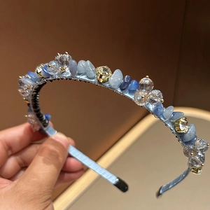 Dettaglio ravvicinato di cristalli azzurri e pietre su un cerchietto avvolto in seta