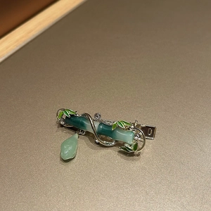 Detail of green bamboo hair clip with elegant silver frame and pearl tassel accents