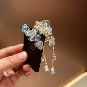 Detail view of crystal flower hair claw with shimmering blue beads and golden tassels