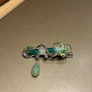 Close-up of green bamboo hair clip with silver metal base and faux emerald drop pendant