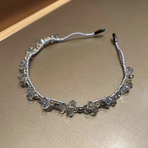 Close-up of elegant slim headband featuring grey crystal beads and golden metal spacers