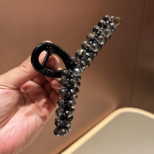 Close-up of a large black hair claw clip with shimmering dark grey crystal beads