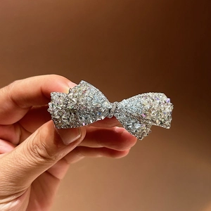 Gros plan sur la barrette à cheveux nœud argentée ornée de strass brillants et ciselés