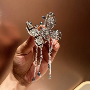 Detailed close-up of a silver butterfly hair claw clip with blue crystal bead tassels