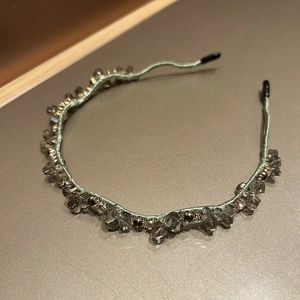 Detailed view of light green satin headband with smoky grey faceted crystals