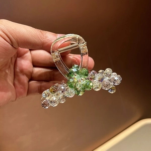 Detail of green crystal and pearl hair claw clip with golden metal spring structure