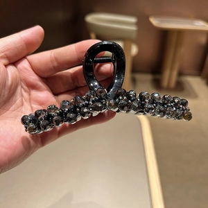 Close-up of elegant black hair claw clip with shimmering dark crystal beads and strong spring