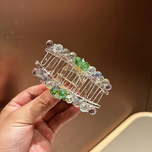Detail showing resin hair claw clip with emerald green rhinestones and gold spring