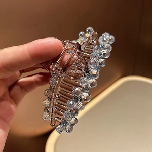 Détail d'une pince à cheveux en acrylique ambré ornée de perles de cristal bleu clair