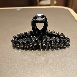 Close-up of elegant black hair claw clip with smoke grey faceted crystal beads decor